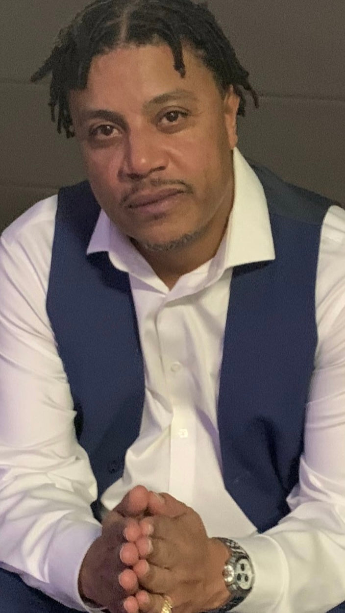 Picture of Ryan Yates, looking directly into the camera hands folded and featuring his hair twisted.